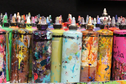 Bottles of various paint chemicals and solvents lined up in a warehouse.