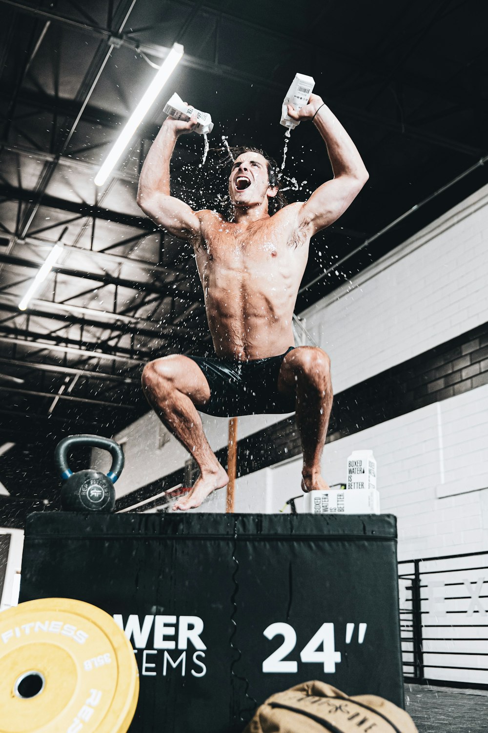 topless man in black shorts holding black and gray exercise equipment