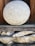 A large, spherical stone with a textured surface rests on a stack of wooden and stone supports. The stone appears weathered, with a natural gray and white speckled pattern. The background includes dark wood panels, contributing to a rustic and earthy atmosphere.