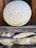 A large, spherical stone with a textured surface rests on a stack of wooden and stone supports. The stone appears weathered, with a natural gray and white speckled pattern. The background includes dark wood panels, contributing to a rustic and earthy atmosphere.