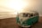 A vintage turquoise and white Volkswagen van parked by the seaside with gentle waves and a bright, hazy sun in the background. The van has a roof rack and its driver-side door is open. The scene exudes a peaceful, nostalgic vibe.
