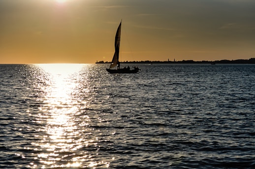 silhouette of sailboat on sea during sunset