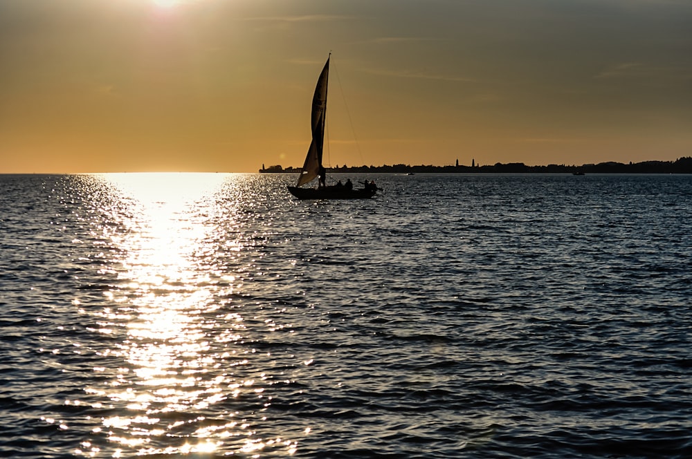 silhouette of sailboat on sea during sunset