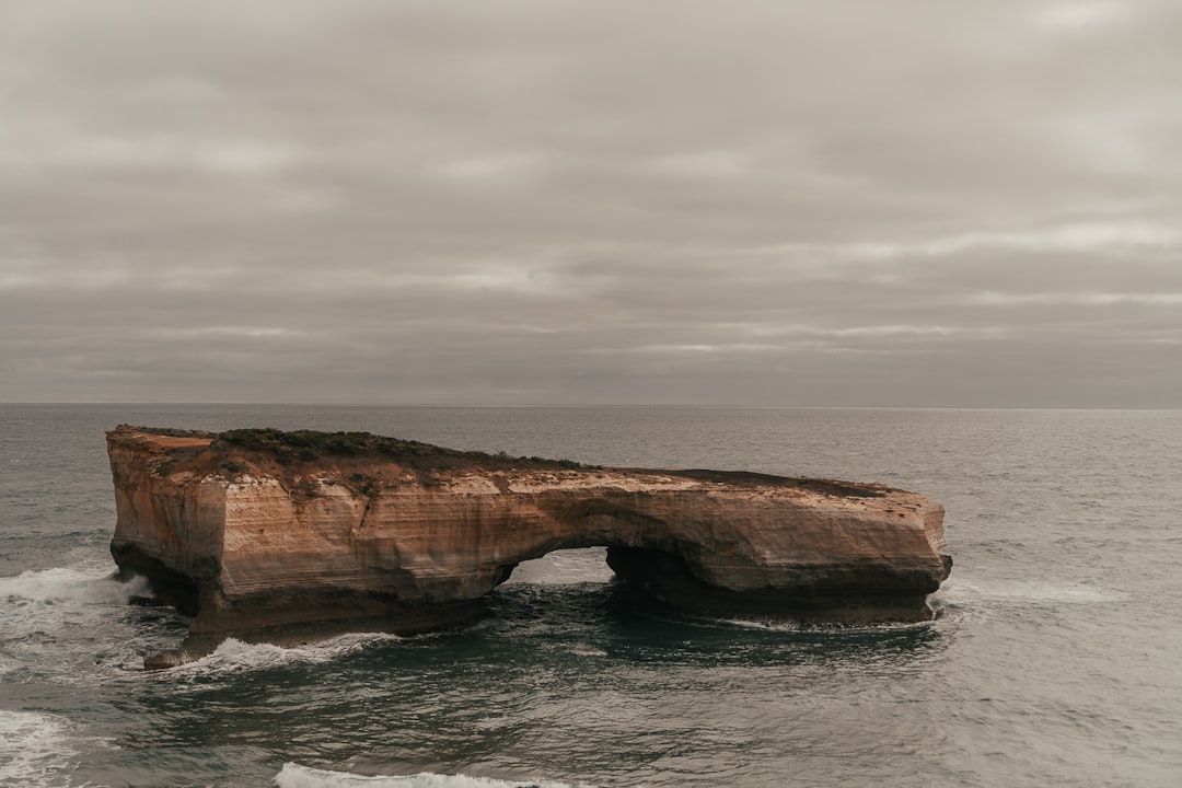 brown rock formation on sea under white clouds during daytime