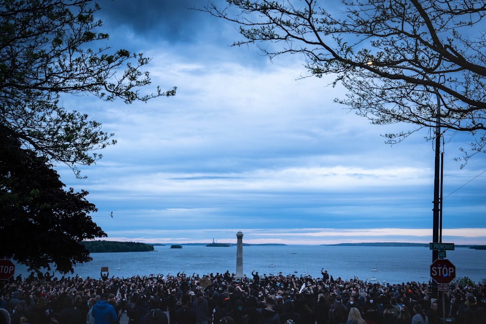 a crowd of people standing around a light house