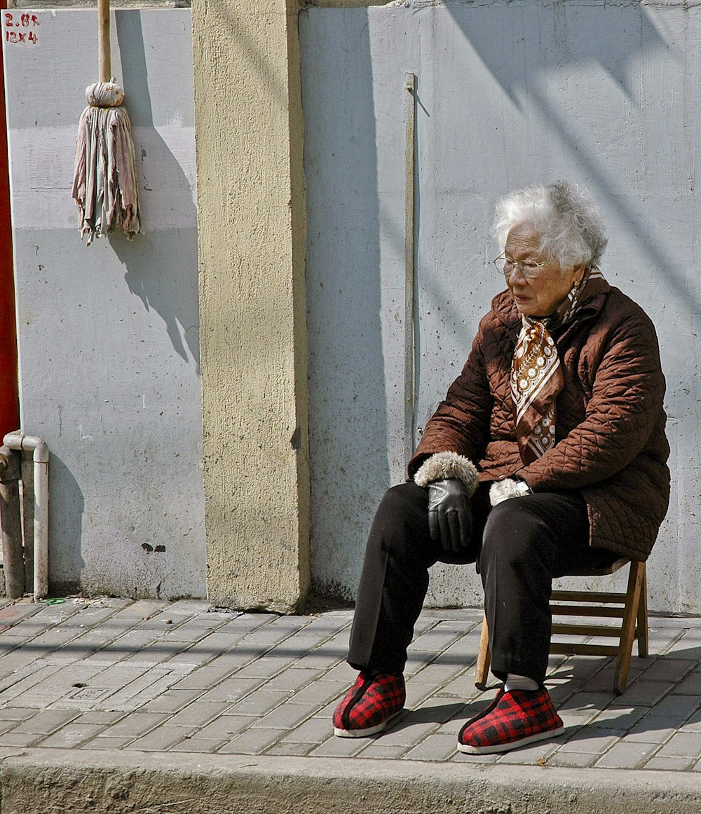 woman in brown jacket sitting on brown wooden chair