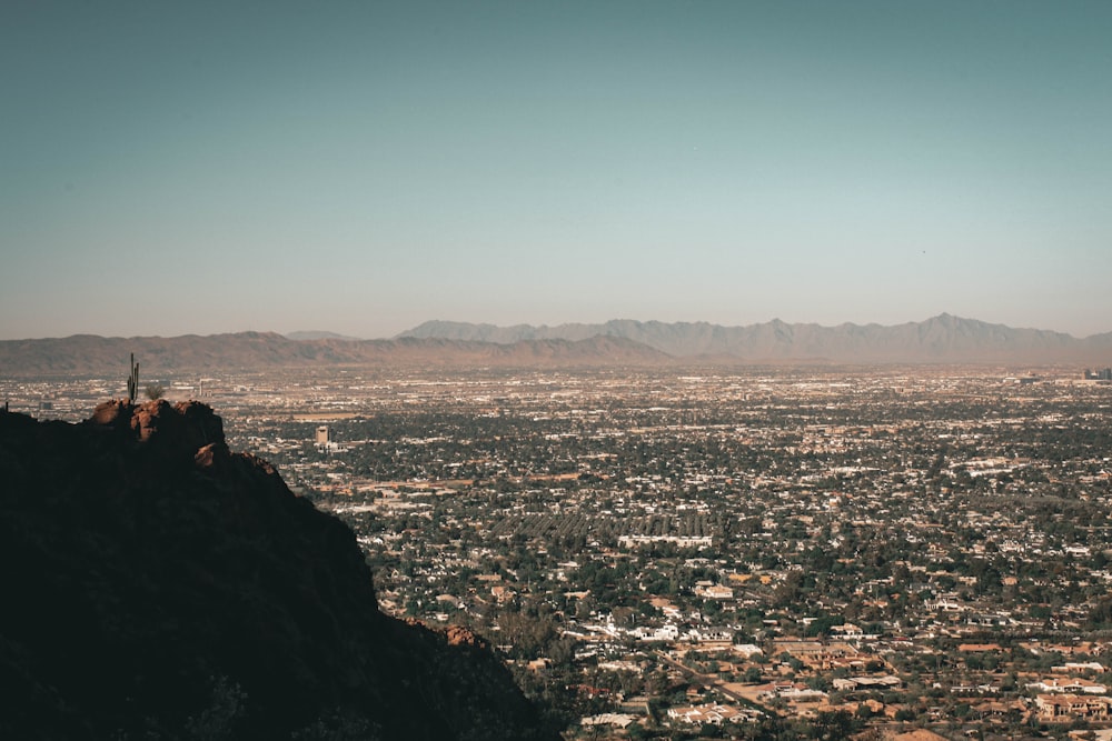 person sitting on rock looking at city during daytime