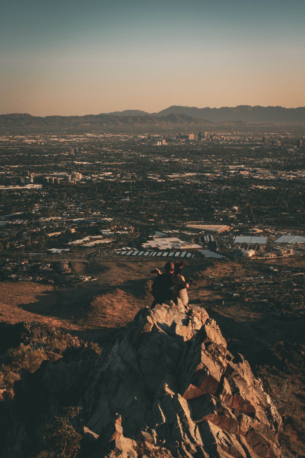 man in black jacket sitting on rock formation during daytime