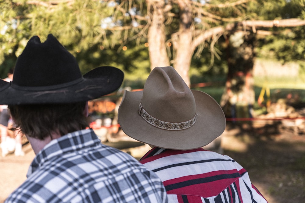 a couple of men standing next to each other wearing cowboy hats