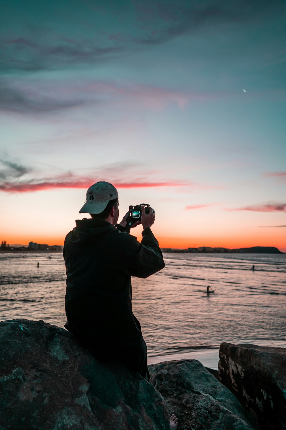 man in black jacket taking photo of sunset