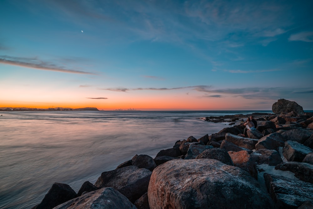 roches brunes près du plan d’eau au coucher du soleil