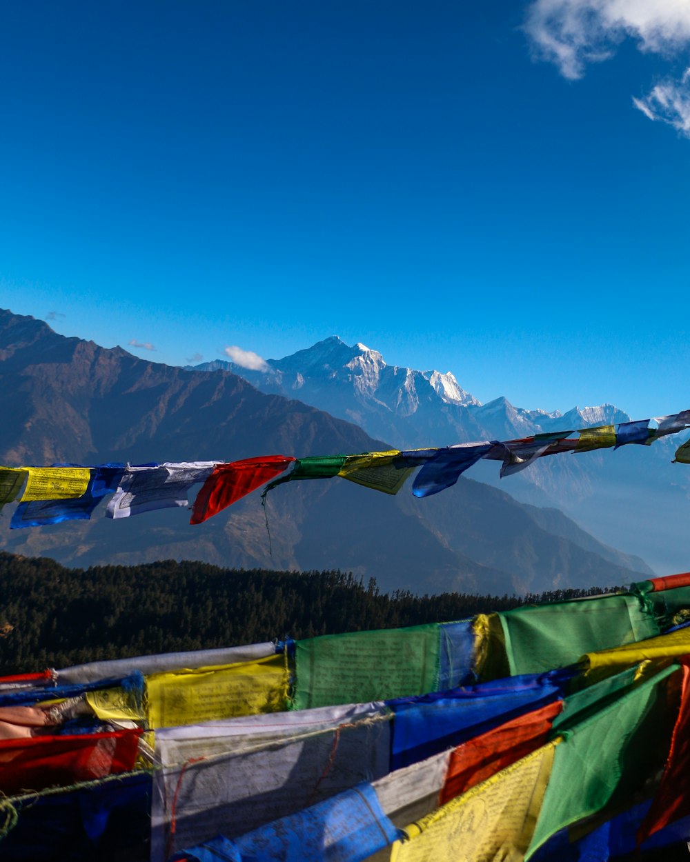 assorted flags on green wooden fence near mountain under blue sky during daytime