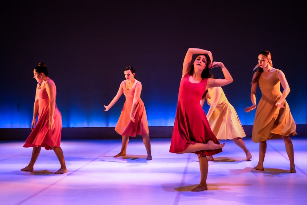 3 women in red dresses dancing on purple floor