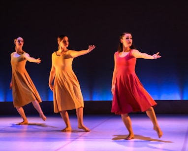 3 women in pink dresses dancing on purple floor