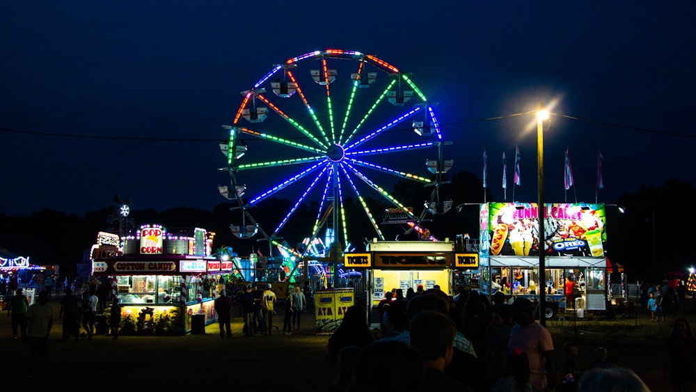 people walking on street with ferris wheel during night time