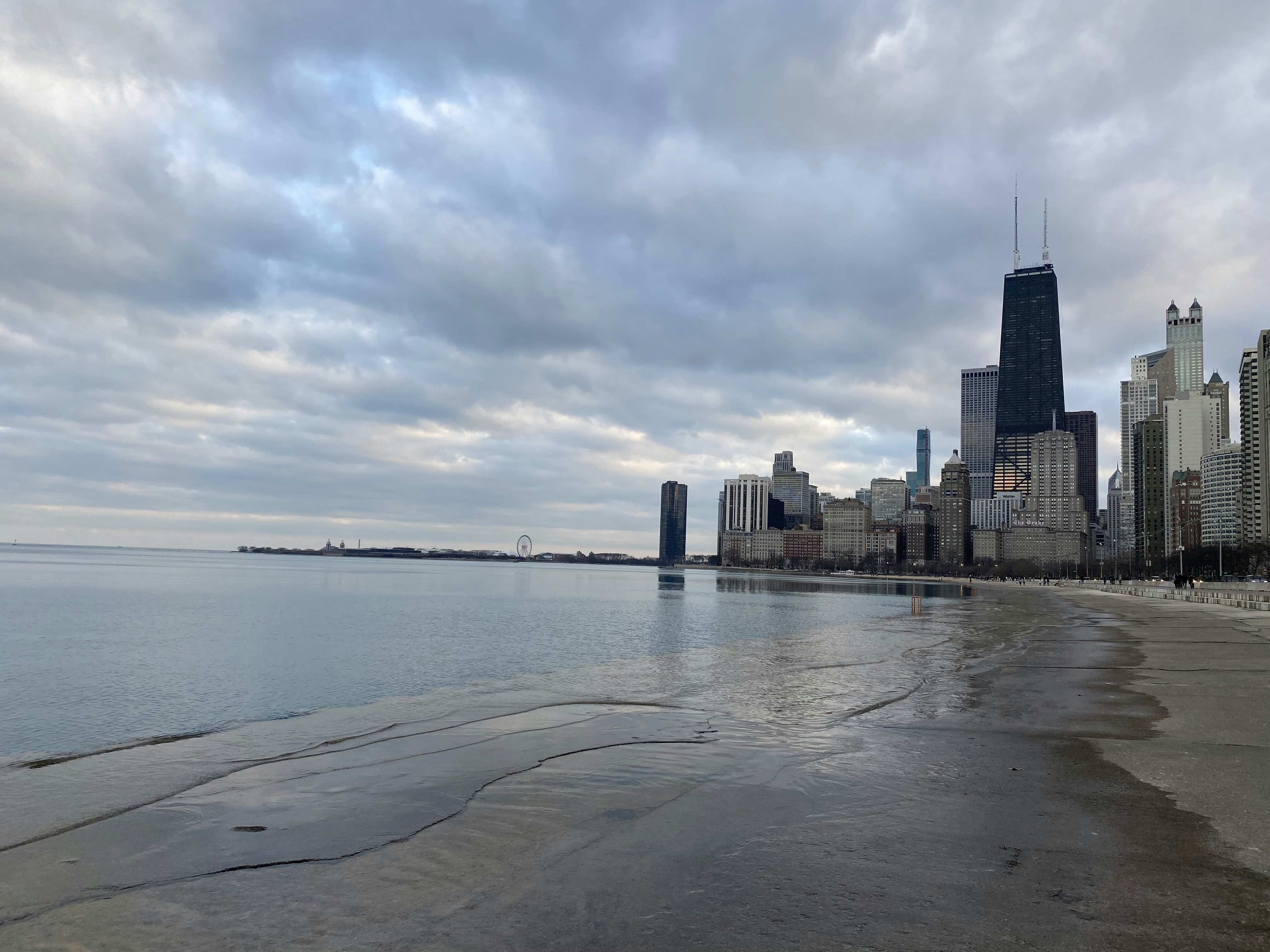 city skyline across the sea under white clouds during daytime