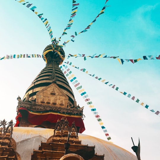 low angle photography of yellow and white concrete building in Swayambhunath Stupa Nepal