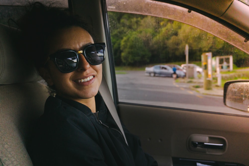 woman in black jacket wearing black sunglasses sitting inside car
