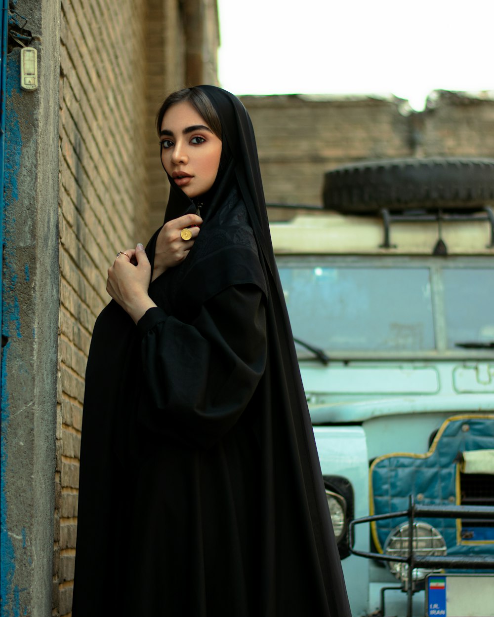 woman in black hijab standing beside brown brick wall during daytime