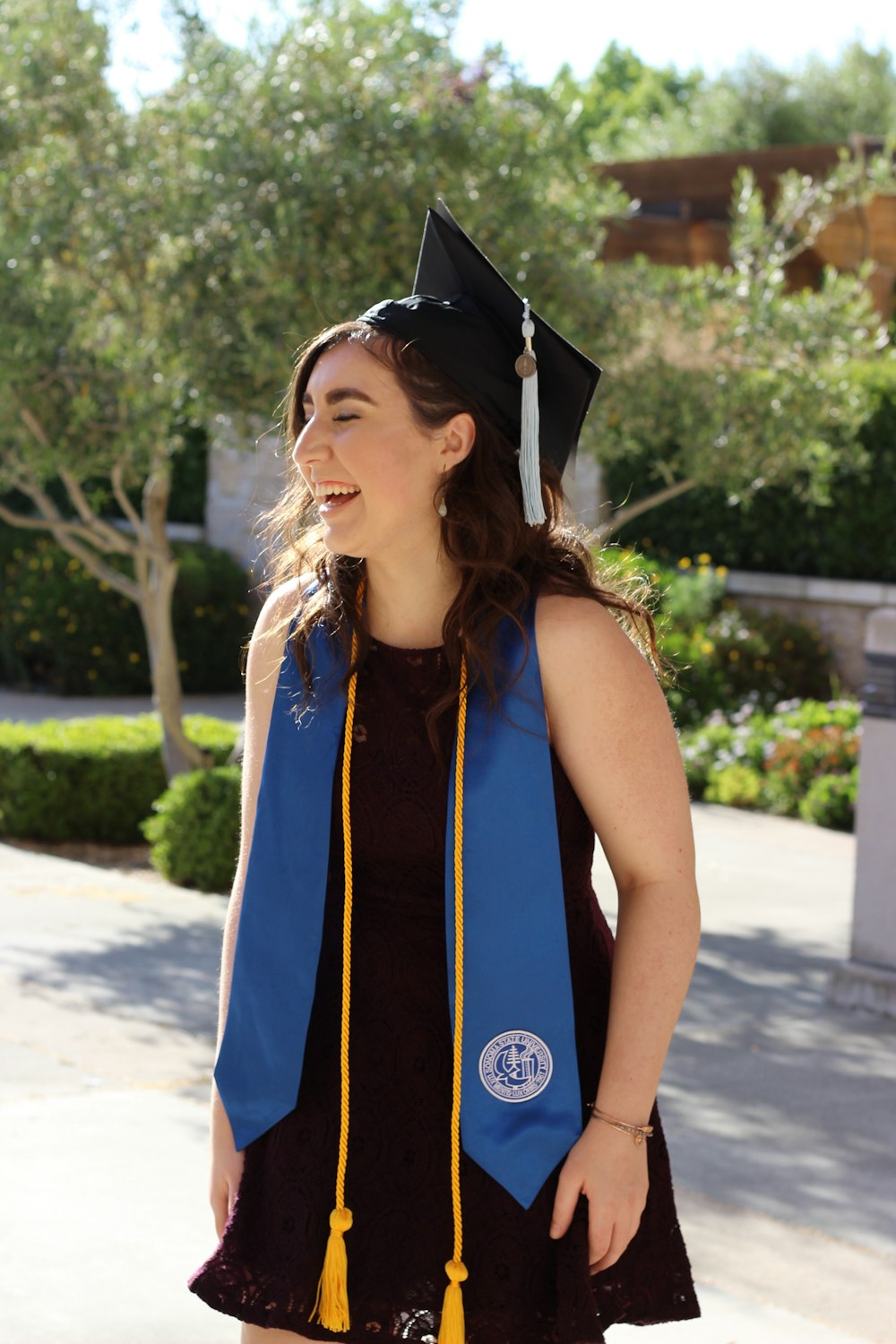 woman in blue and black academic dress standing on road during daytime