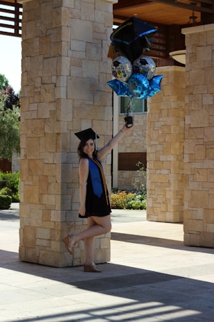 woman in black academic dress standing and smiling