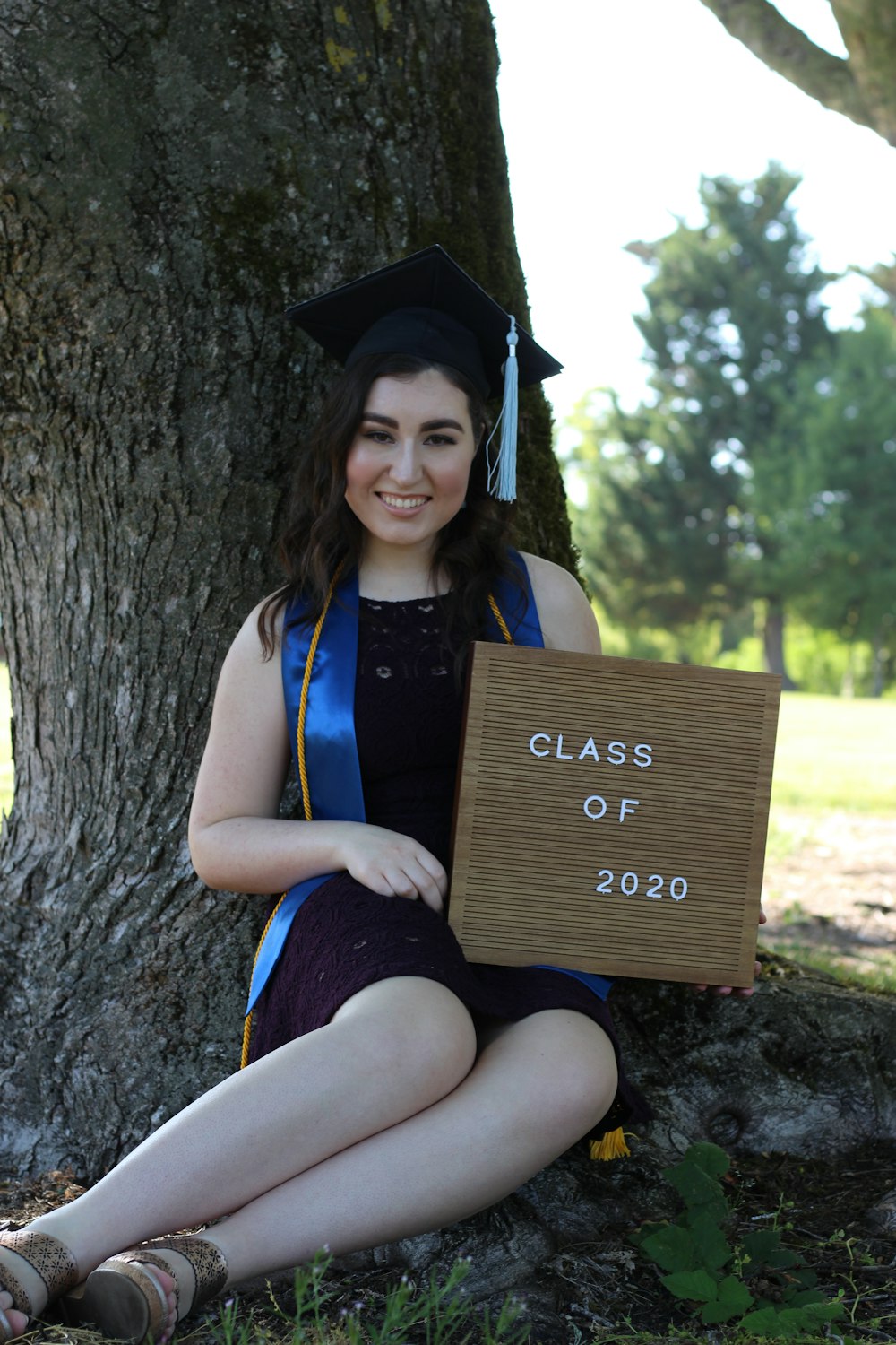 woman in academic dress holding brown wooden box