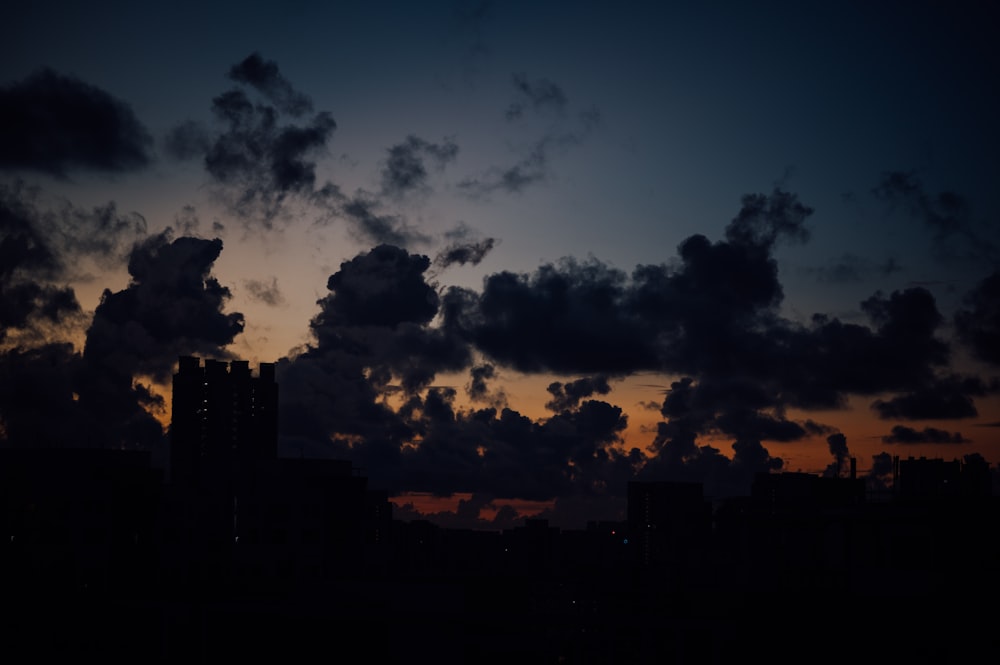 Silhouette von Gebäuden unter bewölktem Himmel bei Sonnenuntergang