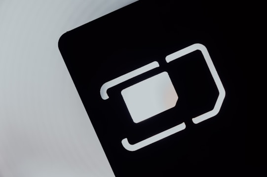 An abstract close-up of a SIM card slot icon, featuring bold, geometric lines and shapes. The negative space is emphasized with a contrasting light gray background and dark, shadowed interior.