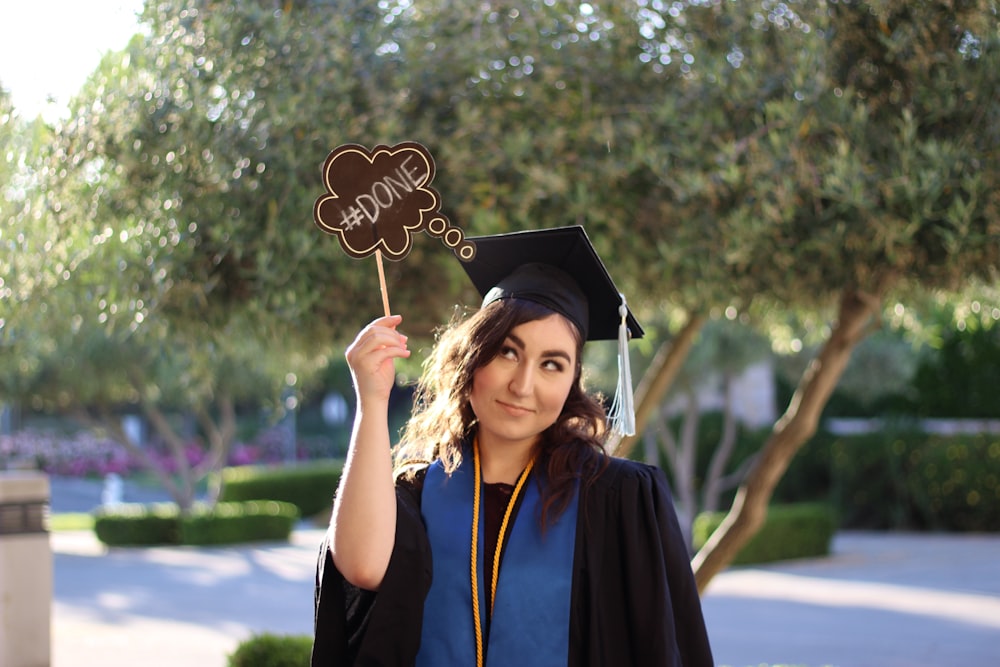 woman in academic dress holding a black academic hat