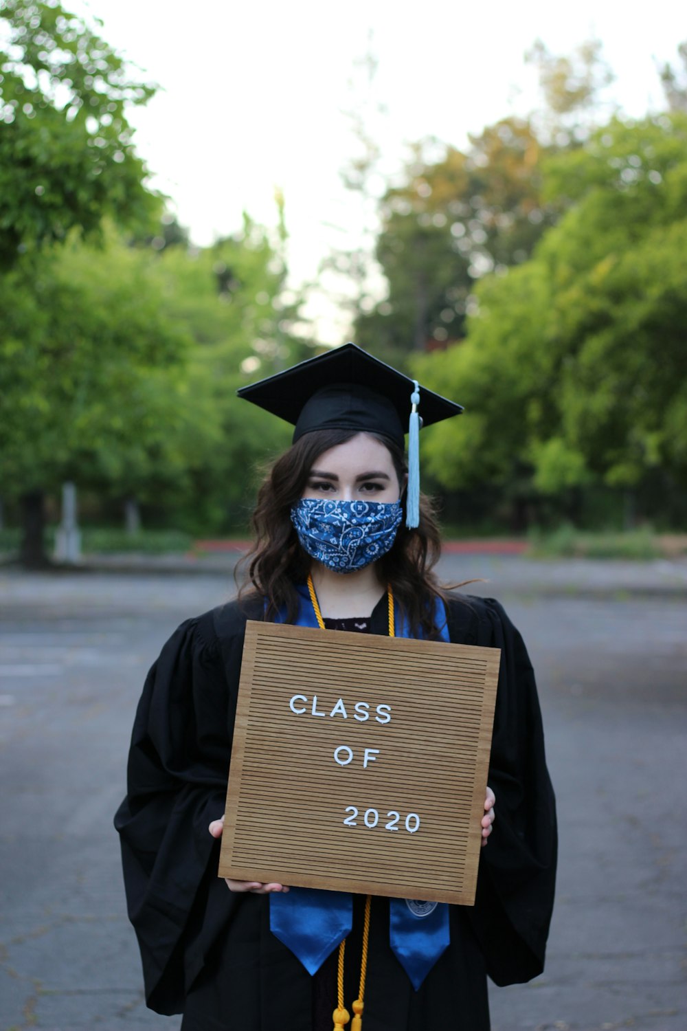 person wearing academic hat holding brown paper bag