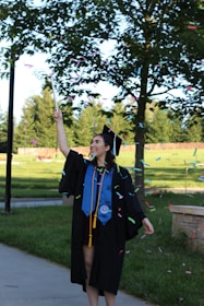 A happy graduate celebrating financial freedom with arms raised outdoors.