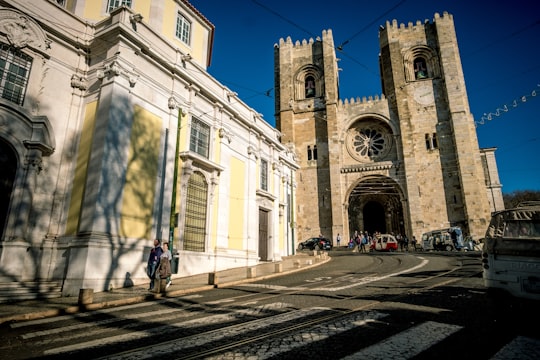 people walking on sidewalk near white concrete building during daytime in Lisbon Cathedral Portugal