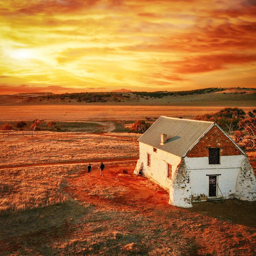 white and brown house on brown field under cloudy sky