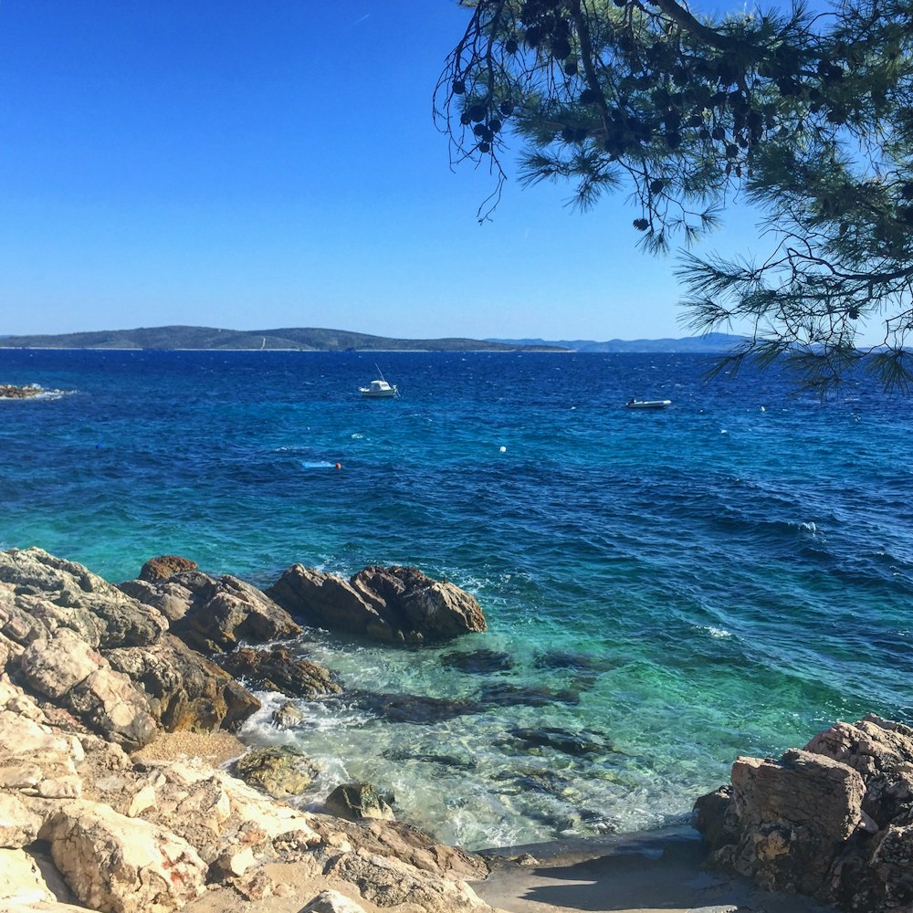 brown rocky shore with blue sea under blue sky during daytime