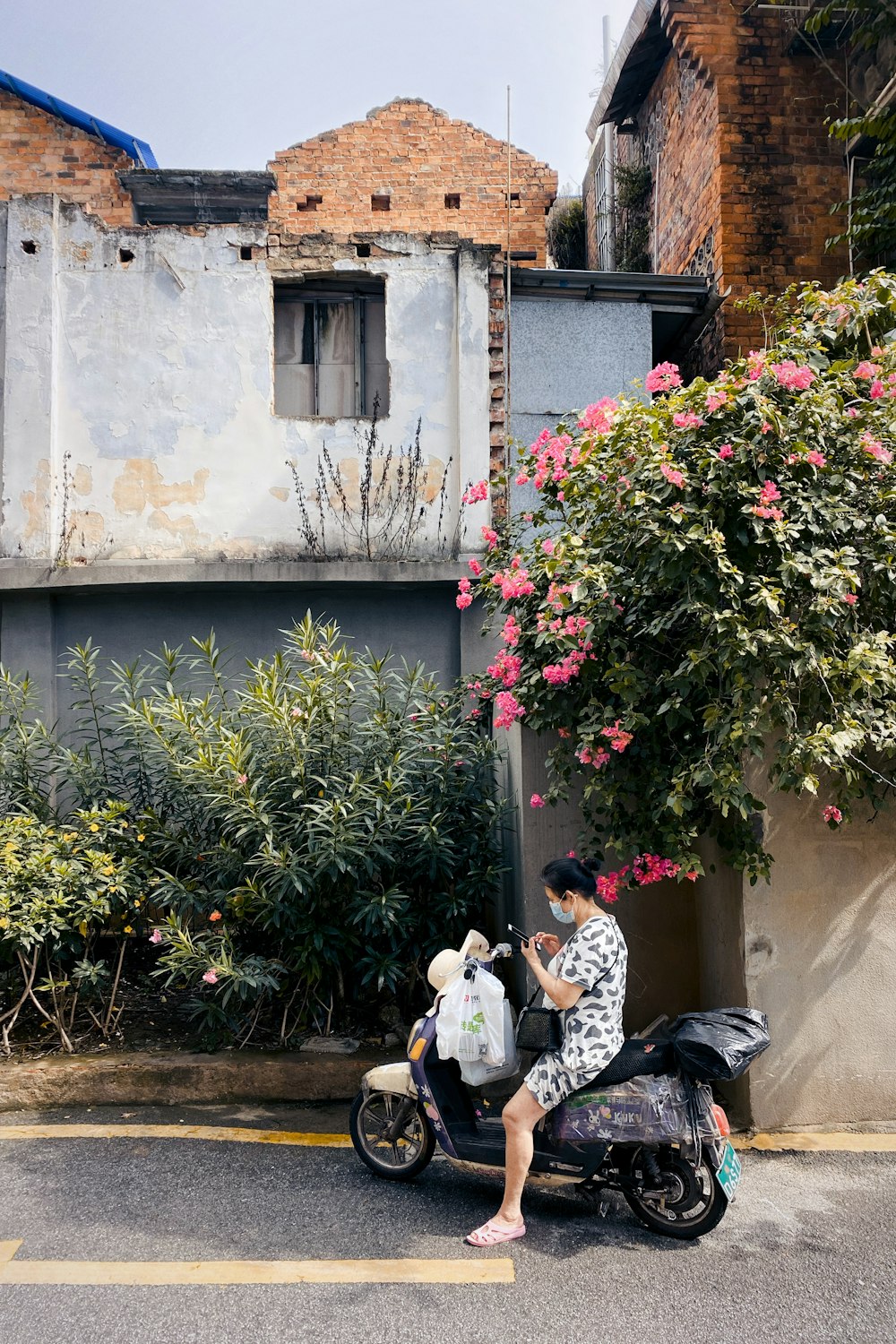 man in white shirt sitting on black motorcycle near green plants during daytime