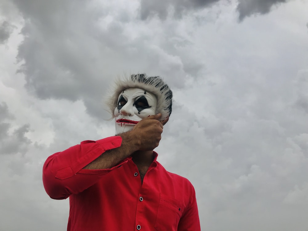 person in red jacket covering eyes with white and black mask