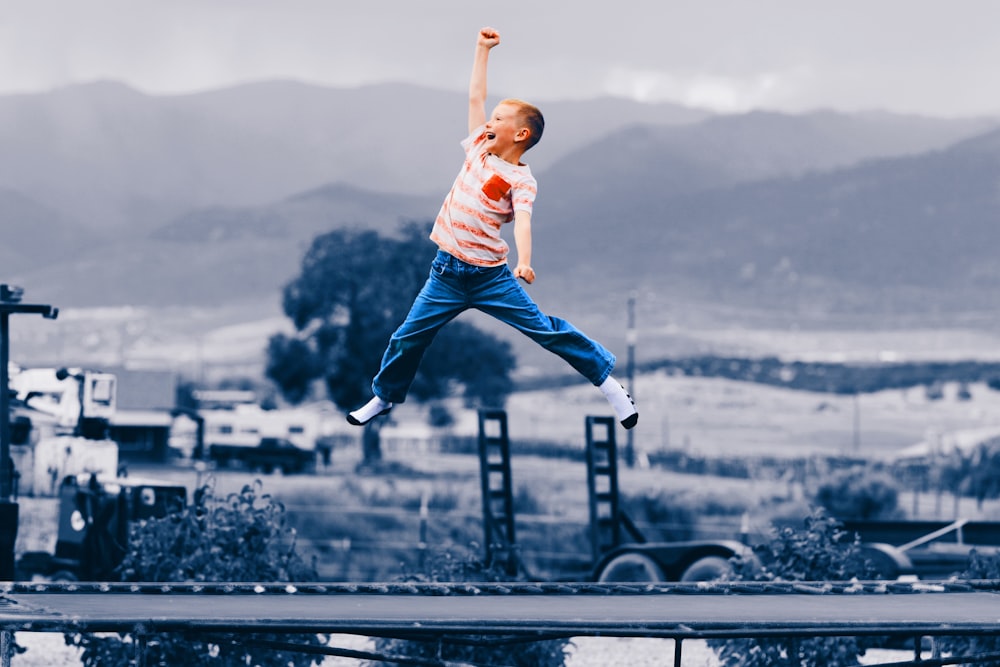 Hombre con camiseta blanca y jeans de mezclilla azules saltando sobre barandillas de metal negro durante el día