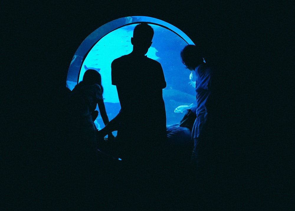 silhouette of man and woman standing in front of blue light