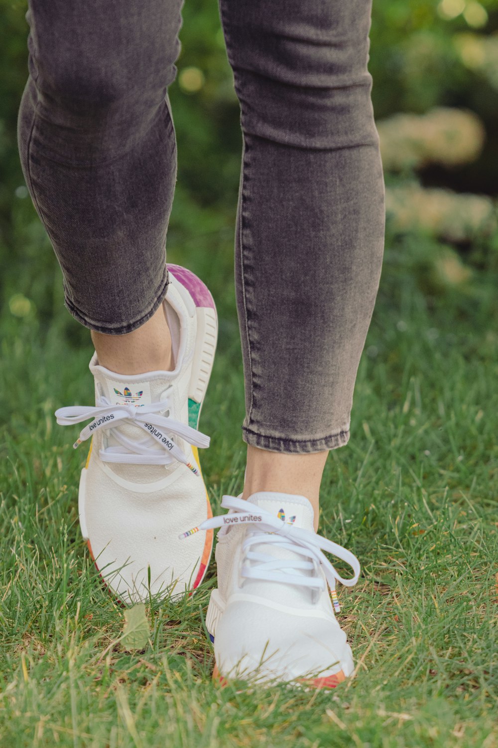 Person in blauen Jeans und weißen Sneakers