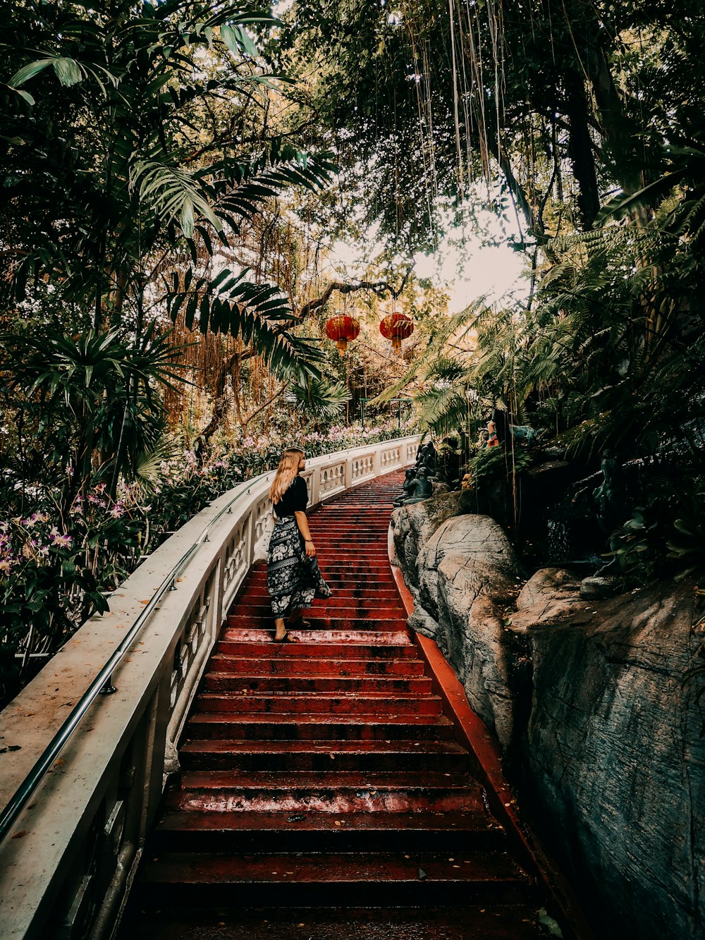 woman in black jacket walking on wooden bridge during daytime