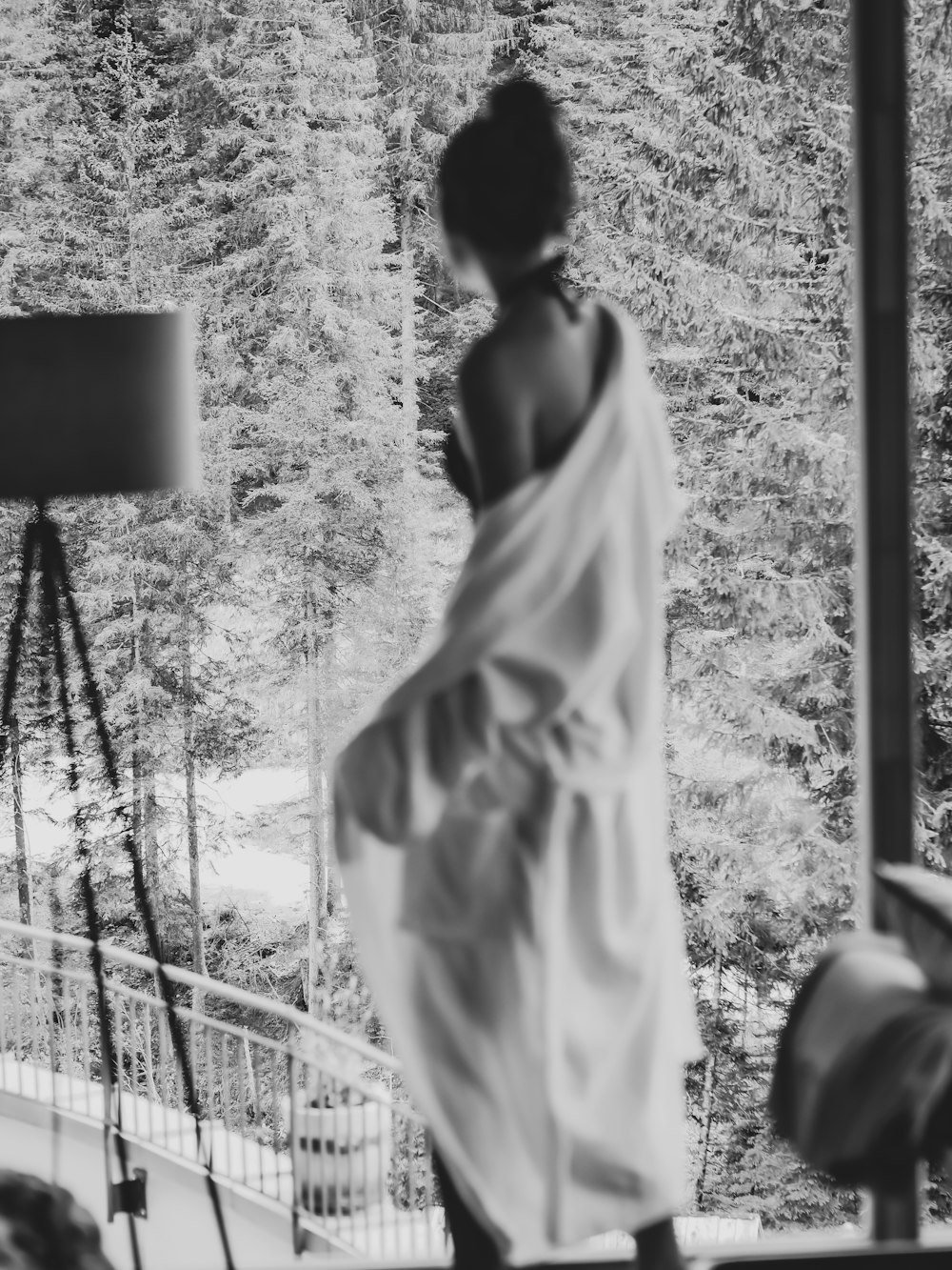 grayscale photo of woman in white dress standing near fence