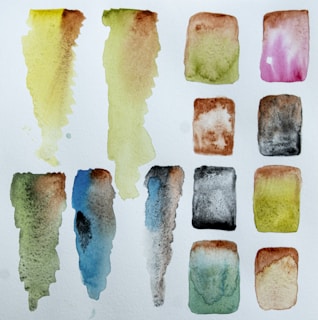 Watercolor swatches blending vibrant blues and greens with a textured paper background.