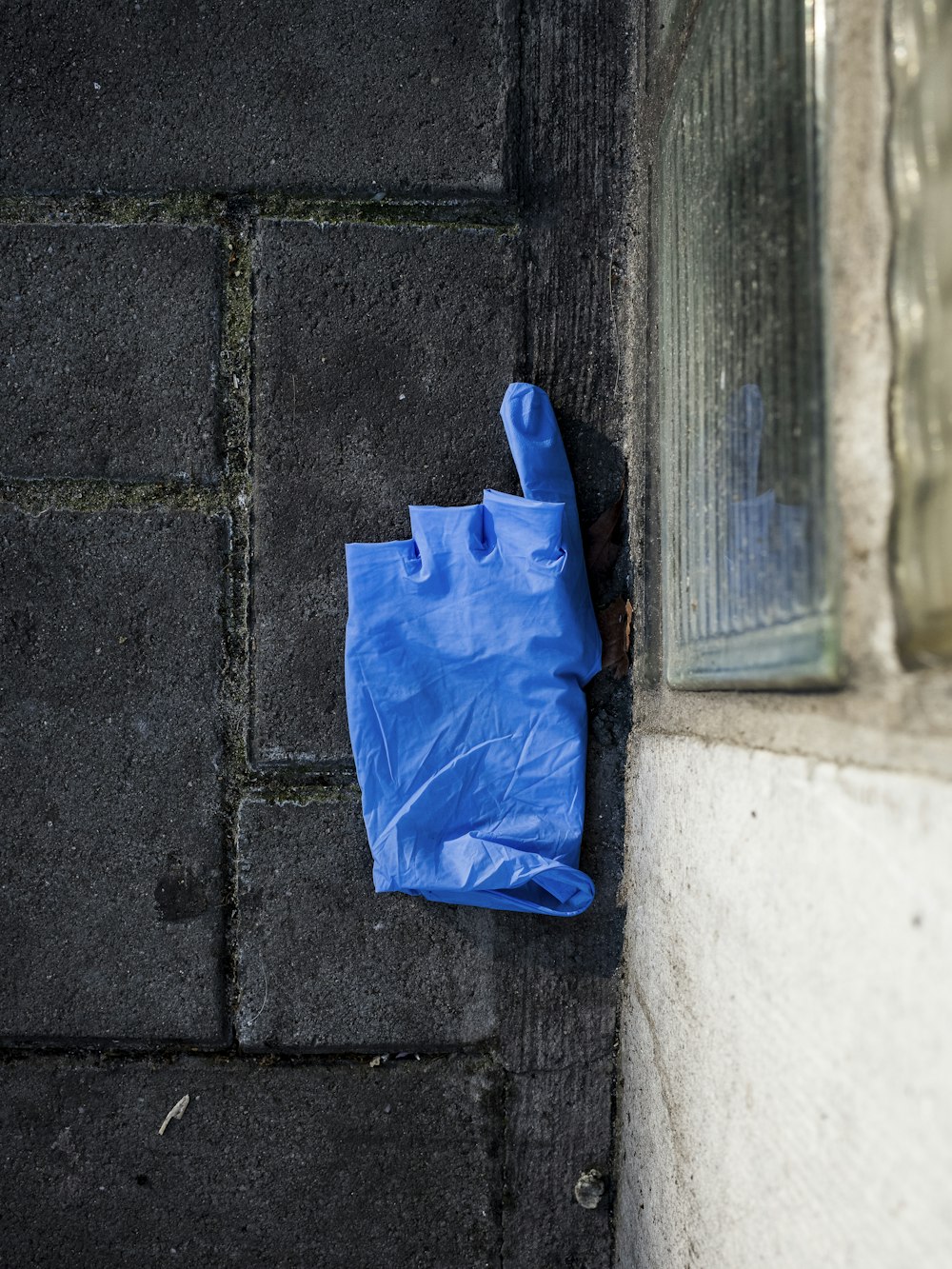 blue plastic bag on gray concrete wall