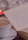 A close-up of a steaming cup of coffee beside a book.