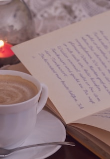 A close-up of a steaming cup of coffee beside open books.