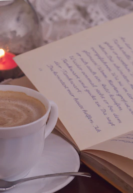 A warm-toned close-up of a steaming coffee cup beside a vintage brass pen on cream parchment.