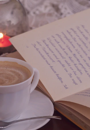 Close-up of hands holding a steaming cup of coffee next to crystals and vintage books.