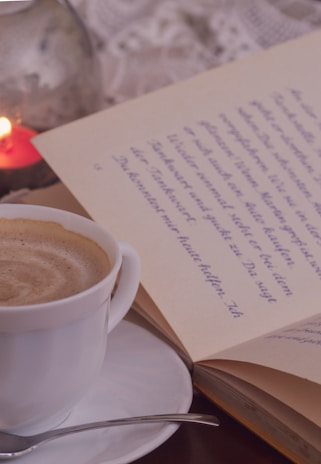 Close-up shot of a handwritten poem on vintage paper beside a steaming cup of coffee.