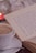 A close-up of a steaming cup of tea next to a cozy book and a candle.