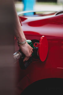 person in red shirt wearing silver bracelet holding red and black metal tool